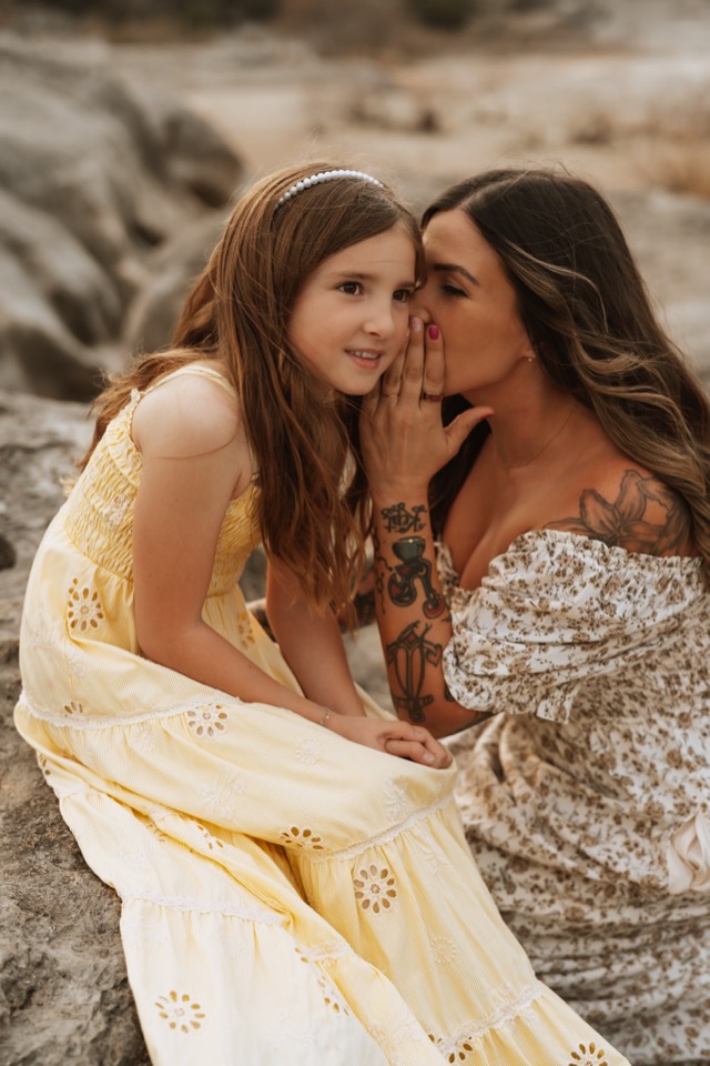 Mother whispering to daughter on the rocks