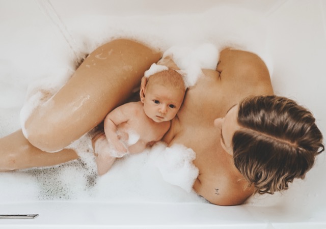 Mother and newborn baby in bubble bath